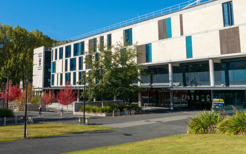 The modern Unipol Recreation Services and Plaza Cafe building seen from across a sunny campus path.